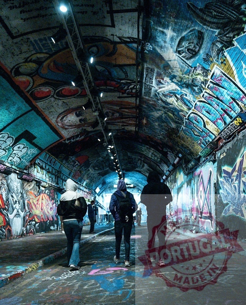 People walking through Leake Street graffiti tunnel in London | People exploring the vibrant street art and graffiti covering the underground tunnel walls - Realized with Pictrs.com