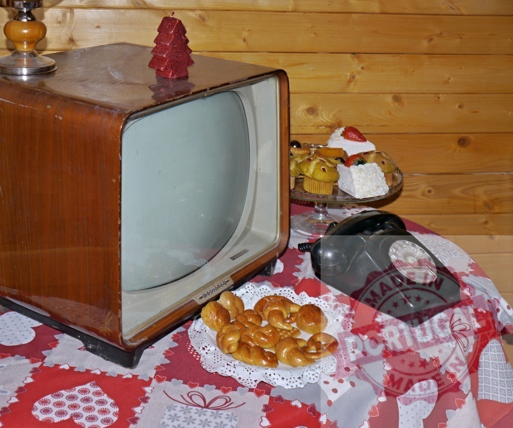 Old television with christmas decorations and pastries showing cozy christmas atmosphere | Vintage television, rotary phone, christmas sweets and red candle on table with christmas tablecloth, creating cozy christmas atmosphere - Realisiert mit Pictrs.com