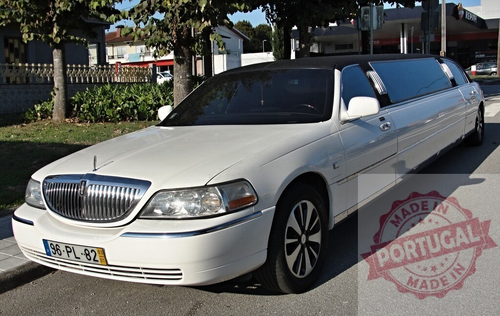 White limousine parked at roadside on a sunny day | White luxury limousine stretching along a street in full sunlight - Realized with Pictrs.com