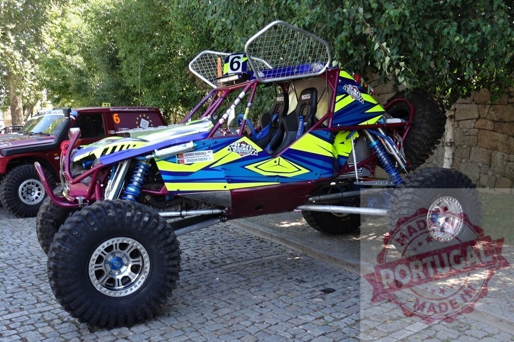 Buggy car parked on a paved road, showing its suspension and big wheels | Customized buggy car with big wheels and exposed suspension parked near a stone wall - Realisiert mit Pictrs.com