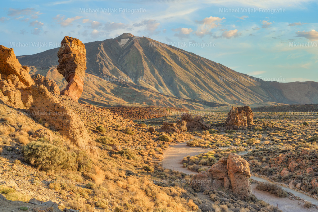 Roque Cinchado und Teide | Der Roque Cinchado ist eine der markantesten Felsformationen auf Teneriffa und ein Symbol der Insel, das oft als "Finger Gottes" bezeichnet wird. Diese einzigartige geologische Formation befindet sich im Teide-Nationalpark, einem UNESCO-Welterbe, und steht in beeindruckendem Kontrast zum Vulkan Teide, Spaniens höchstem Berg. Die Landschaft um den Roque Cinchado herum ist geprägt von einer vielfältigen Geologie und einer reichen Geschichte vulkanischer Aktivität, die Besucher aus aller Welt anzieht. - Realisiert mit Pictrs.com