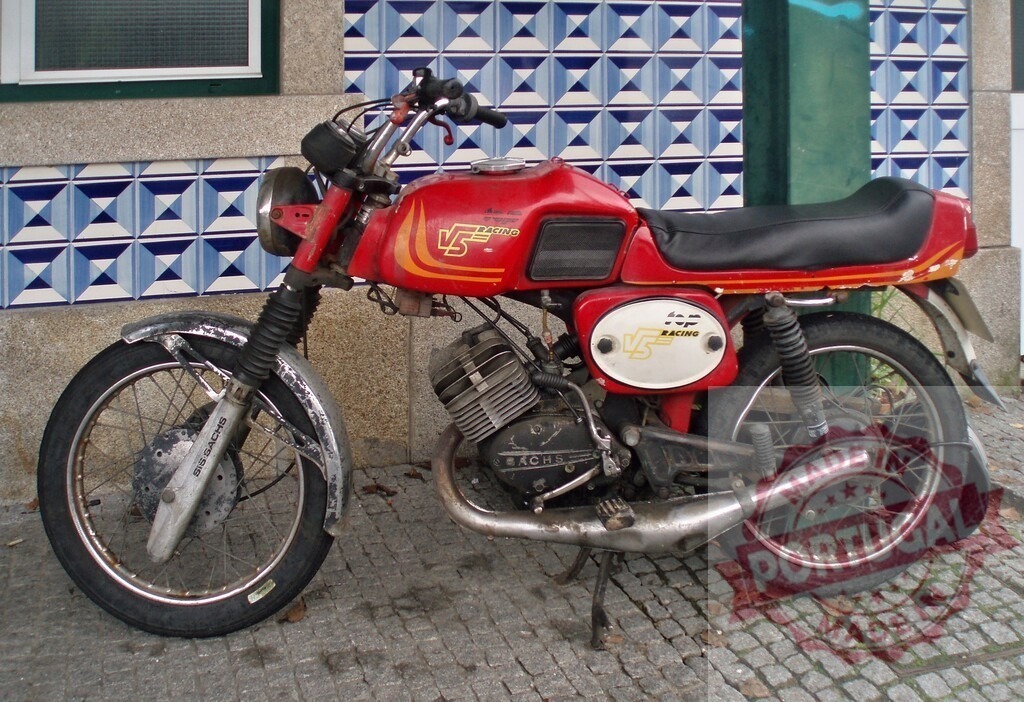 Red casal v5 racing motorcycle parked near a tiled wall | Old red casal v5 racing motorcycle parked near a tiled wall in the city - Realized with Pictrs.com