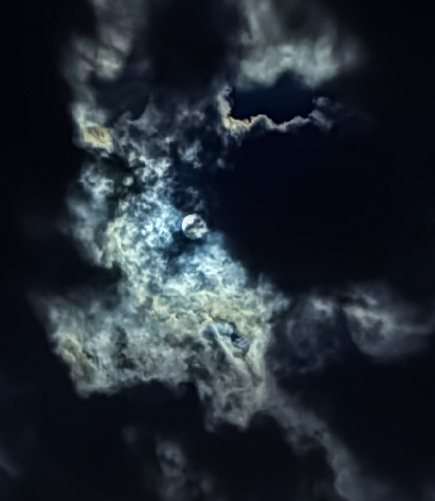 Nachtakzente – Mondlicht I | Dramatische Kunstfotografie des Mondes, der sich durch eine dichte, vom Licht inszenierte Wolkendecke bricht. Diese mystische Aufnahme fasziniert durch tiefe Kontraste und eine fast malerische Textur. Ein exklusives Wandbild für Räume, die Ruhe, Tiefe und zeitlose Eleganz ausstrahlen sollen. - Realisiert mit Pictrs.com