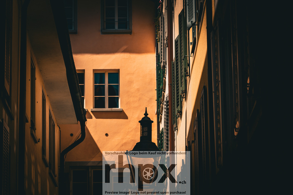 Lichtspiel im Brandgässli | Licht. Schatten. Geborgenheit.Die warme Nachmittagssonne taucht die schmalen Gassen der Luzerner Altstadt in ein goldenes Licht. Zwischen historischen Fassaden und traditionellen Laternen entfaltet sich ein faszinierendes Spiel aus Helligkeit und tiefen Kontrasten.Wähle unter "Produktauswahl" dein Wunschformat: Vom klassischen Wandbild über Puzzle &amp; Tassen bis zum digitalen Download (z.B. als Handy-Hintergrund). - Realisiert mit Pictrs.com