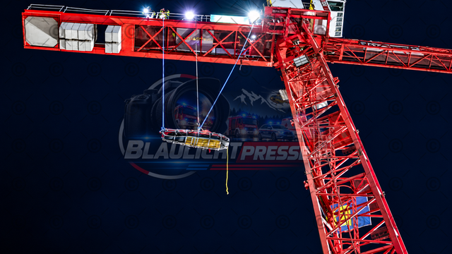 Menschenrettung von Baukran | Symbolbild für Einsätze oder Übungen mit einem Baukran oder auf einem Baukran. Rettungstrage hängt von Baukran. Menschenrettung am Baukran. Nächtliche Rettung am roten Baukran - Realisiert mit Pictrs.com