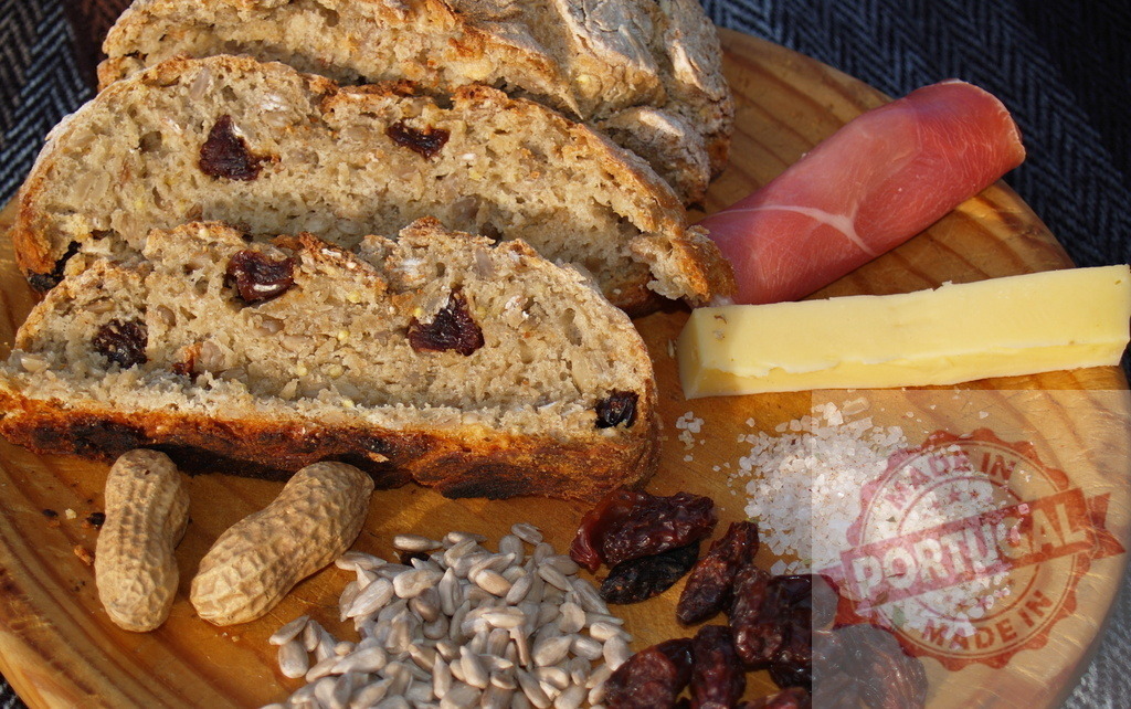 Rustic platter preparing ingredients for healthy snack | Rustic wooden platter presenting fresh bread, peanuts, seeds, dried fruit, ham, cheese, and salt - Realized with Pictrs.com