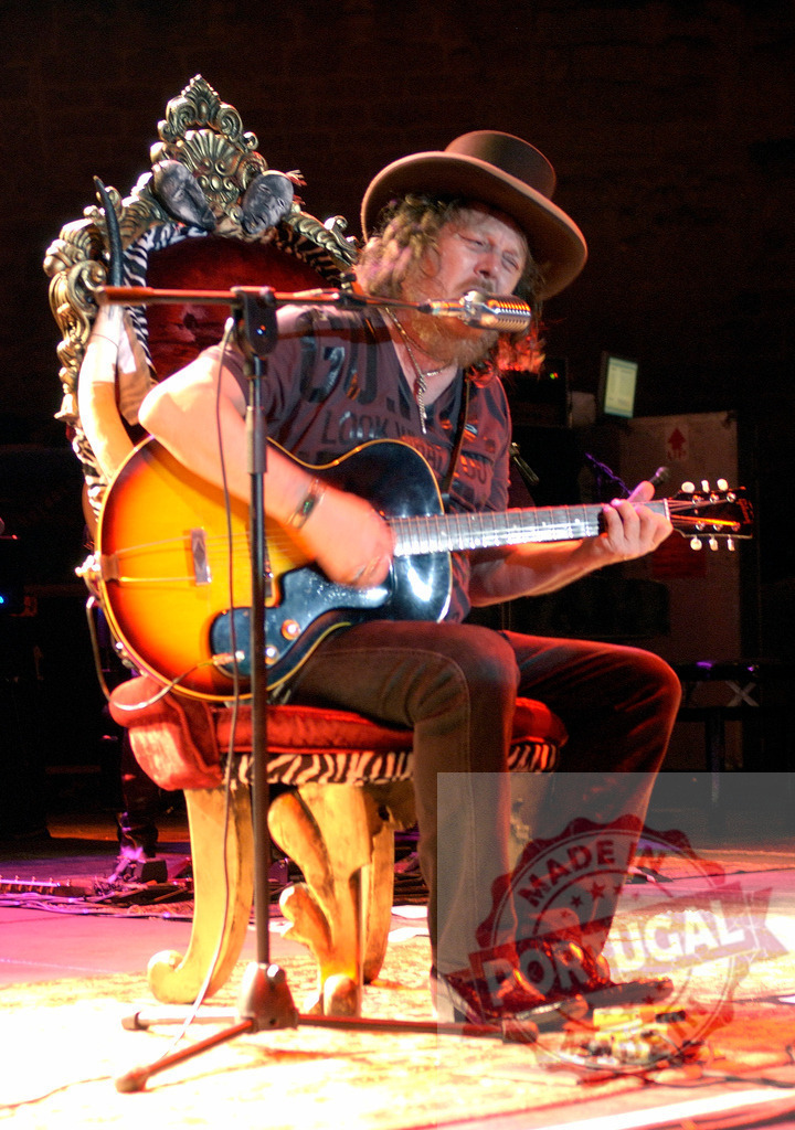 Musician playing guitar and singing, sitting on a throne on stage | Country musician playing guitar and singing, sitting on a throne on stage - Realized with Pictrs.com