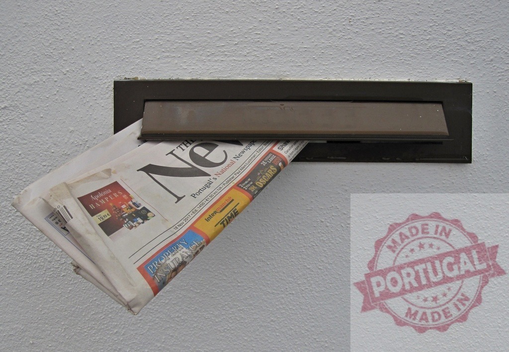 Newspaper Sticking Out of Mail Slot in White Wall | Folded newspaper sticking out of a mail slot in a white wall, suggesting recent delivery - Realisiert mit Pictrs.com