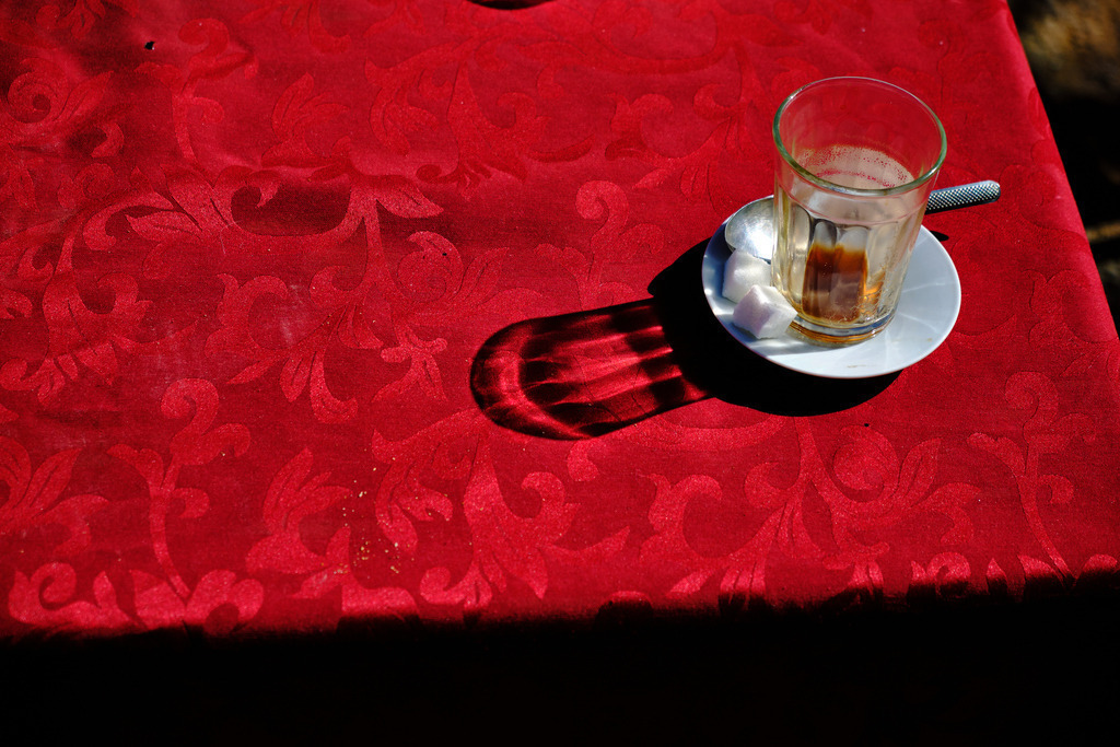 Leeres Glas Kaffee mit Schatten auf roter Tischdecke | Marokko - November 21, 2024: Leeres Glas Kaffee mit Schatten auf roter Tischdecke. - Realisiert mit Pictrs.com