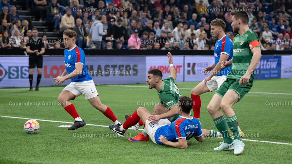 SHFV Lotto Masters 2024 | 20240113_7174, 13.01.2024, SHFV Lotto Masters 2024, Gruppe B, Holstein Kiel (blau) vs. PSV Neumünster (grün), Jan Wansiedler (Holstein #2) &amp; Tim Siedschlag (Holstein #21) / Tim Möller (PSV #21) &amp; Fyn Claasen (PSV #23) - Realisiert mit Pictrs.com