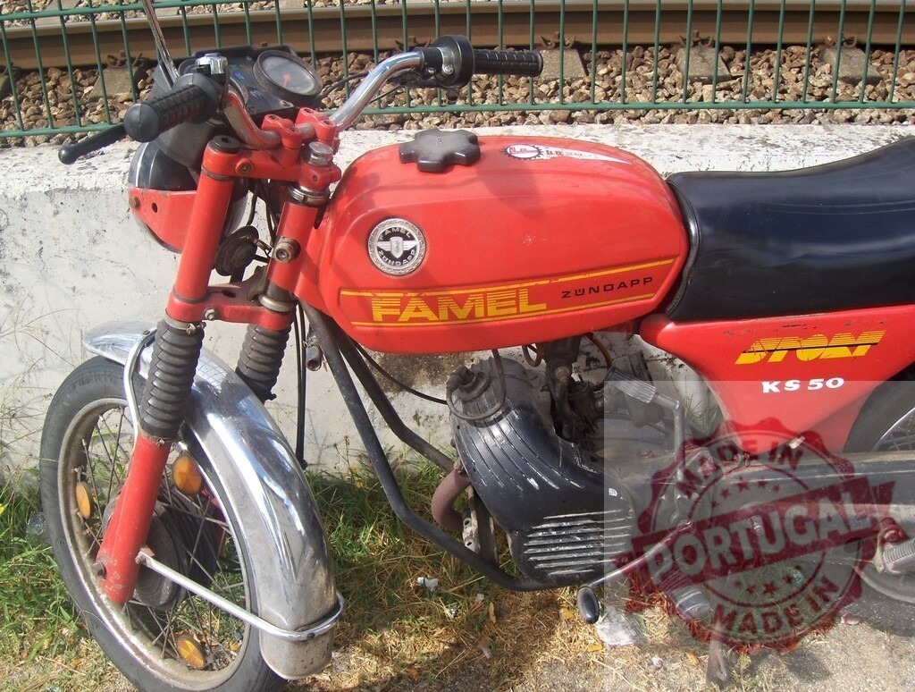 Red Famel KS 50 Motorcycle Parked near Railroad Tracks | Classic red Famel KS 50 motorcycle parked near railroad tracks, showcasing vintage design and transportation - Realized with Pictrs.com