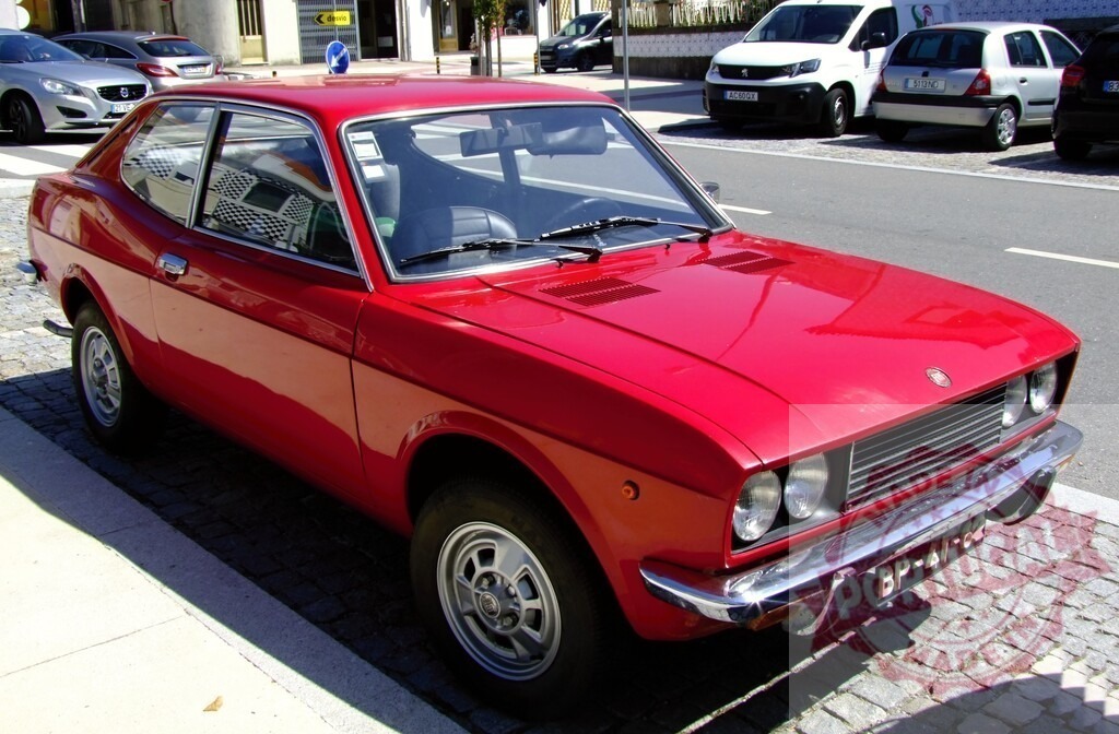 Red Fiat 128 Sport classic car parked on street | Red Fiat 128 Sport Coupe parked on a sunny paved street - Realisiert mit Pictrs.com