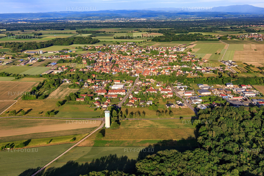 Vue aérienne: Vue de la ville depuis l'ouest, derrière le château d'eau à Sundhouse dans le département Bas Rhin, France. Photo: IMG_147359.jpg prise le 29/05/2025 par Werner Riehm/FLY-FOTO.eu – Résolution de l'original: 5472 x 3648 px