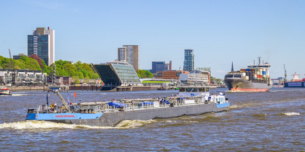 Walter Deymann, Binnentankschiff | Die Walter Deymann ist ein 84 Meter langes Binnentankschiff, das 2009 gebaut wurde. Das Bild zeigt die Walter Deyman, wie sie in Hamburg elbabwärts fährt, im Hintergrund befindet sich u. a. das einem Schiff nachempfundene Gebäude Dockland. - Realisiert mit Pictrs.com