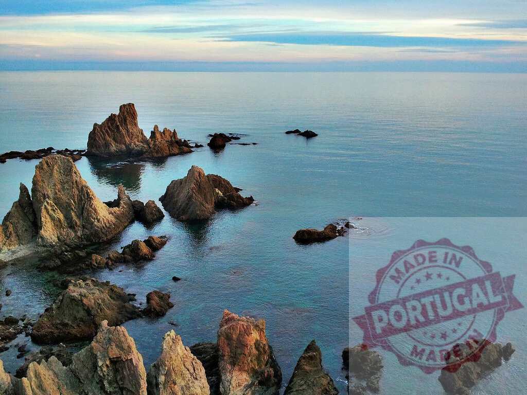 Rocky coastline emerging from the turquoise mediterranean sea at sunset | Jagged rocks emerging from the calm turquoise water of the mediterranean sea at sunset - Realized with Pictrs.com