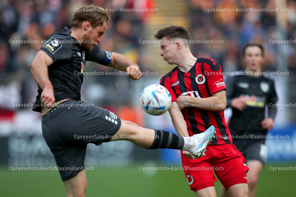 Koe3Liga17042301012 | 17.04.2023, Köln, Fußball, bwin 3. Liga Herren, Sportpark Höhenberg, 32. Spieltag, Saison 2022 2023, FC Viktoria Köln – MSV Duisburg: Sebastian Mai von MSV Duisburg schießt den Ball - Robin Meißner von FC Viktoria Köln duckt sich weg. DFB regulations prohibit any use of photographs as image sequences and or quasi-video.