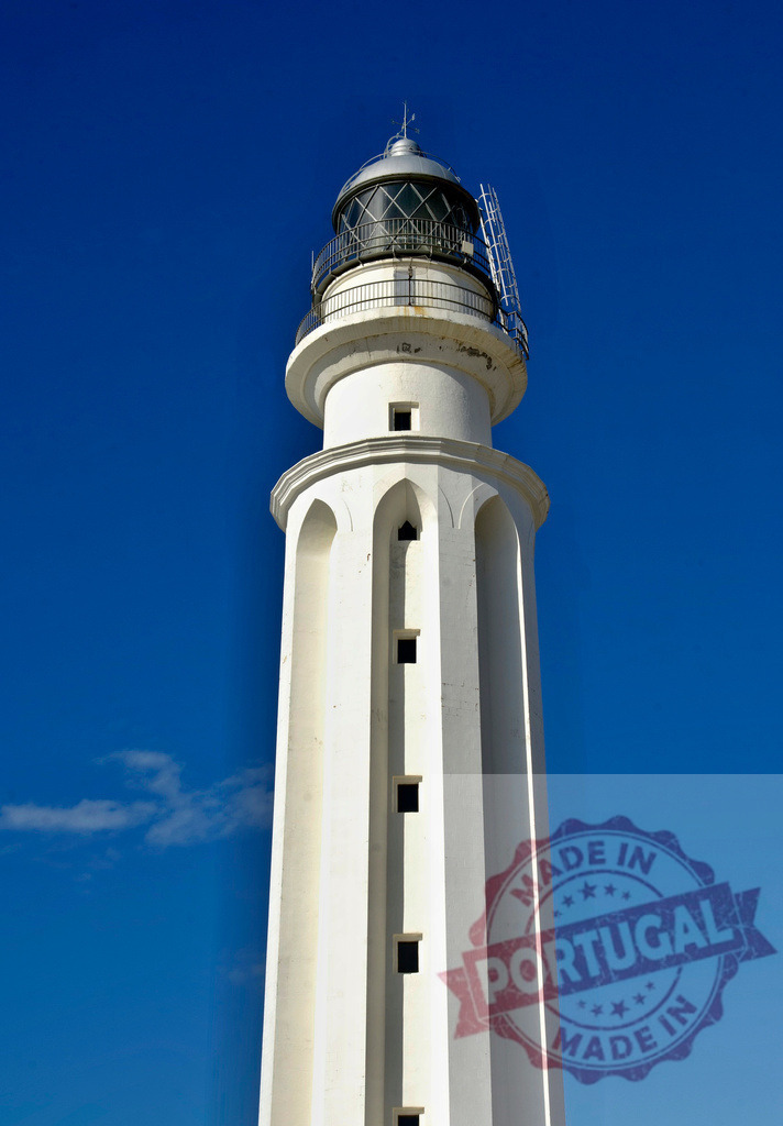 Cape Trafalgar lighthouse guiding ships along Spanish coast. Espana - Cadiz | White navigation lighthouse standing tall under a clear blue sky - Realized with Pictrs.com
