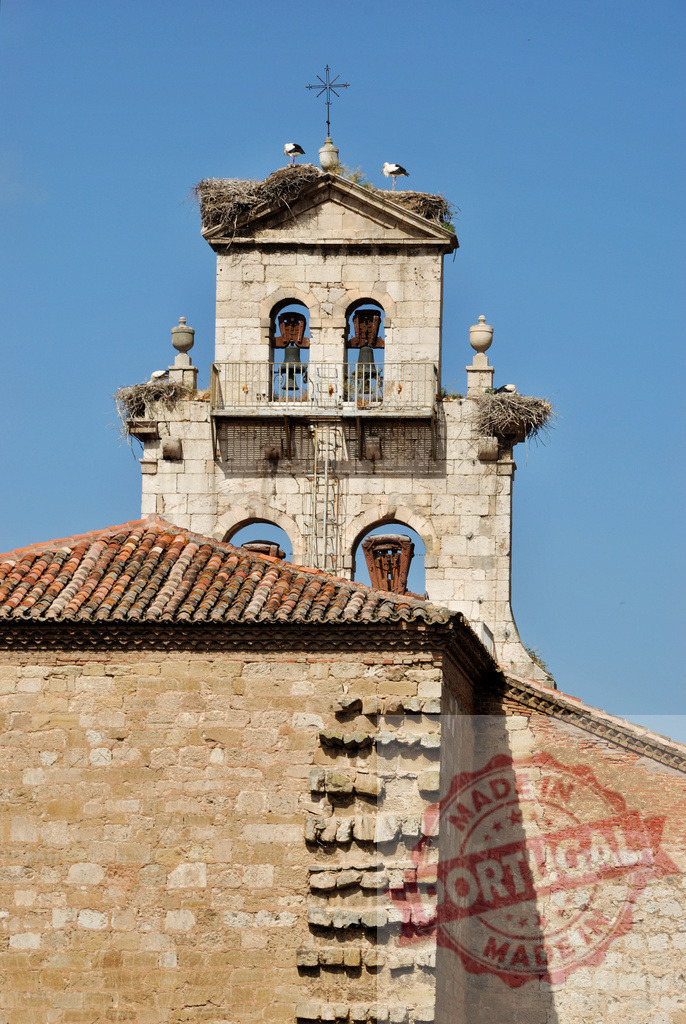 Storks nesting on historic bell tower in Spain. Spain - Burgos | Storks building nests on a stone bell tower under a clear blue sky - Realized with Pictrs.com