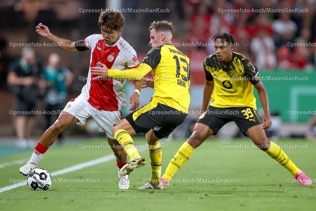 DFB18082501056 | 2025.08.18, Fußball, 1.Runde DFB-Pokal, Rot-Weiss Essen - Borussia Dortmund, Stadion Hafenstraße, Saison 2025 2026: Kaito Mizuta&nbsp;(Rot-Weiss Essen #24) im Zweikampf gegen  Pascal Groß&nbsp;(BVB #13) und Filippo Mane&nbsp;(BVB #39)  DFB regulations prohibit any use of photographs as image sequences and or quasi-video.