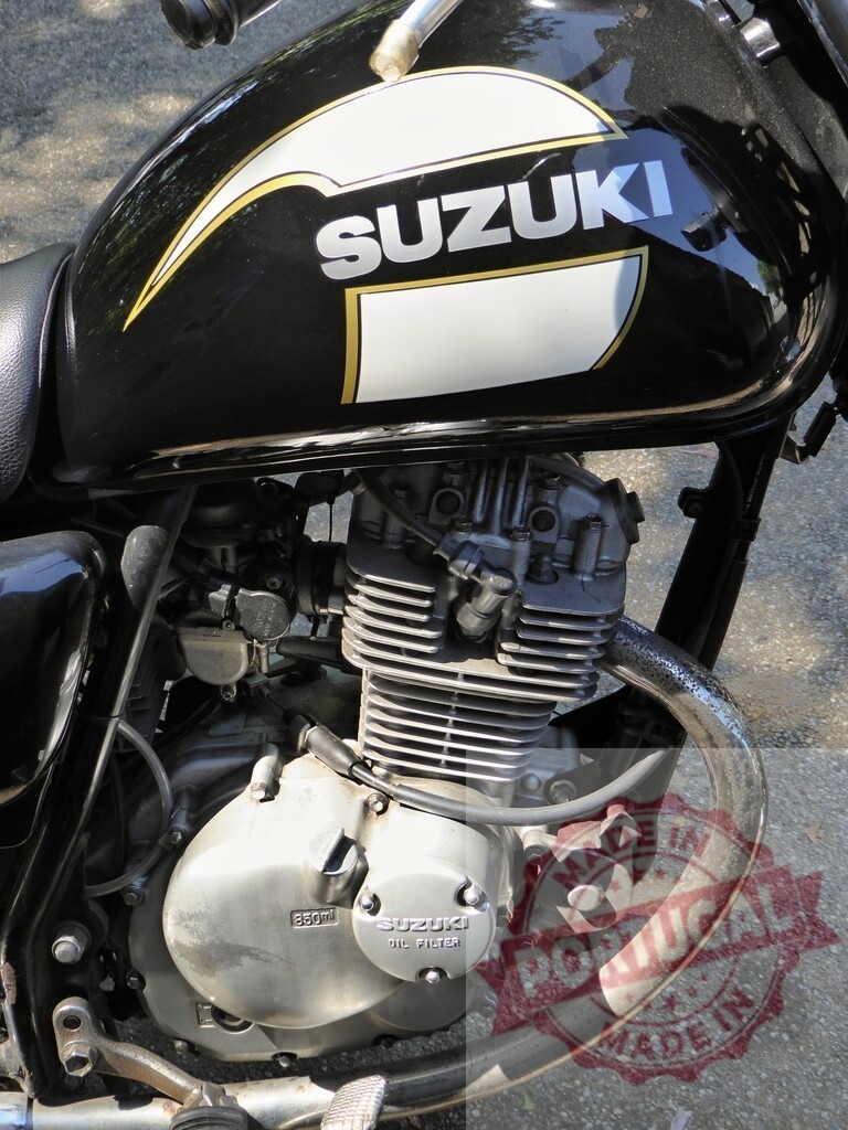 Close-up of Suzuki Motorcycle Engine and Fuel Tank | Motorcycle engine and fuel tank showcasing Suzuki branding, highlighting the details of a classic motorbike design - Realisiert mit Pictrs.com