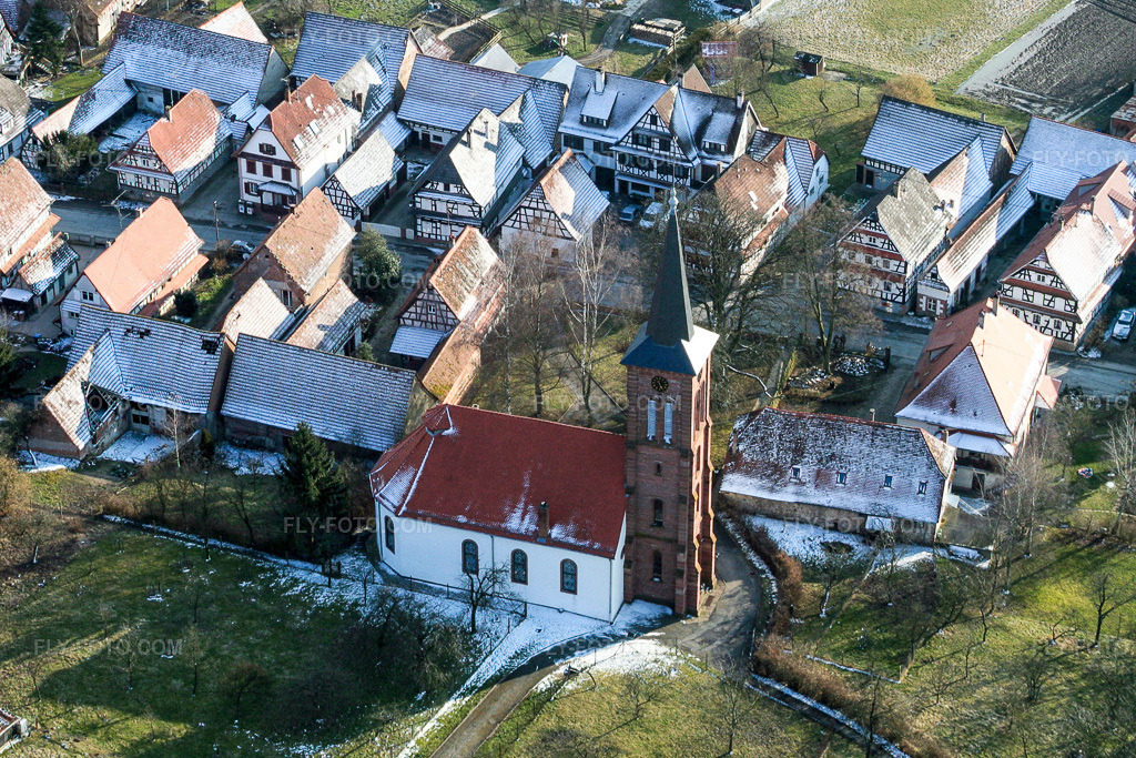 Aerial view: Wintery snow-covered Protestant Church Hunspach in the village center in Hunspach in the state Bas-Rhin, France. – Photo: IMG_1220b.jpg taken on 03/12/2006 by Werner Riehm/FLY-FOTO.com – Resolution of the original: 2605 x 1737 px