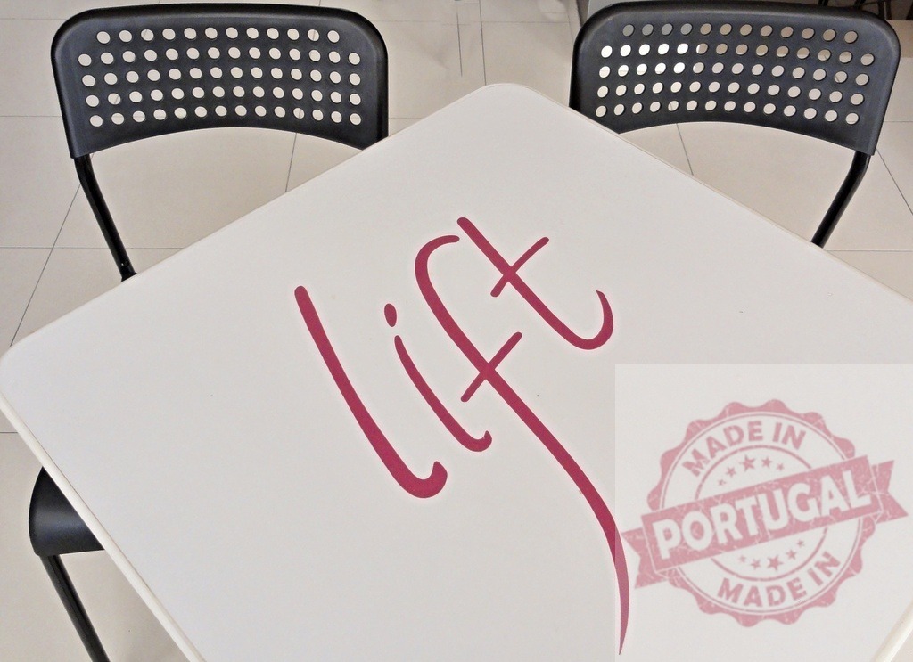 White table with word lift and two chairs | White table featuring the word lift in magenta with two black chairs in a minimalist setting - Realisiert mit Pictrs.com
