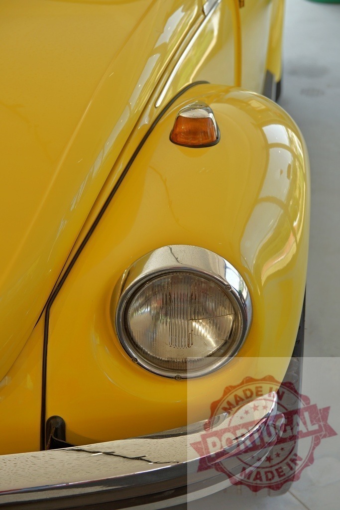Close-up of yellow Volkswagen Beetle headlight and turn signal | Shiny yellow Volkswagen Beetle featuring a prominent headlight and turn signal, showcasing classic car design - Realisiert mit Pictrs.com
