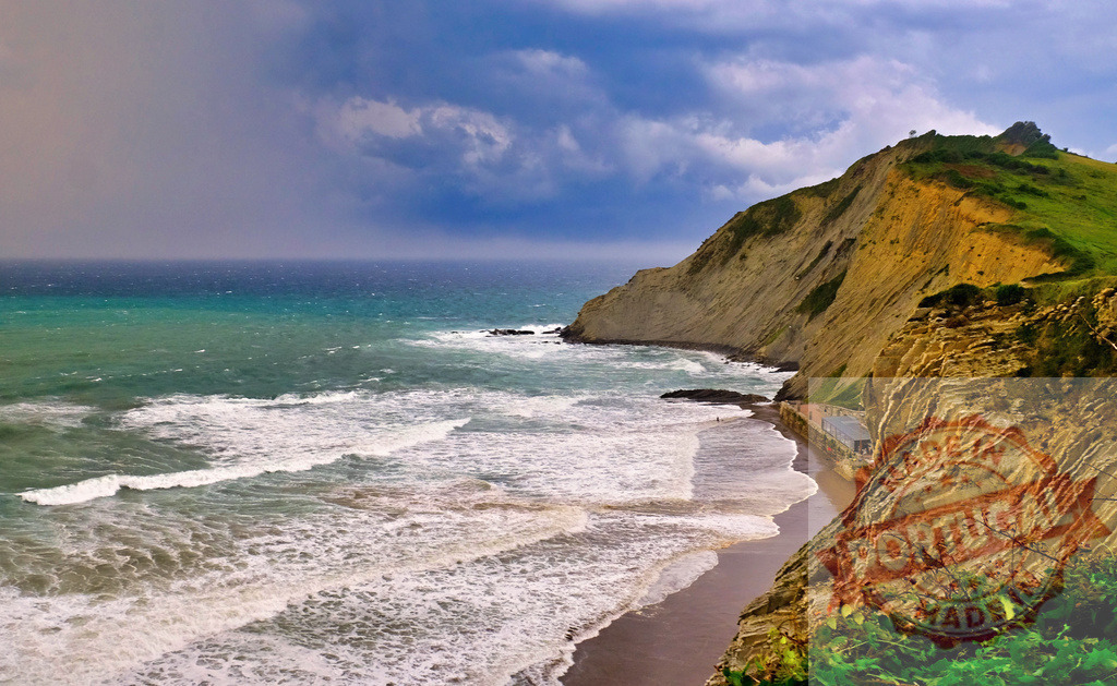 Flysch rock formations along a dramatic Basque coast | Ocean waves crashing on a sandy beach next to layered geological cliffs under a cloudy sky - Realisiert mit Pictrs.com