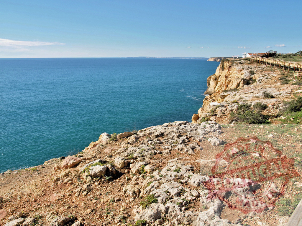Algarve coastline with wooden boardwalk by the Atlantic Ocean | Rocky cliffs and a wooden boardwalk overlook the blue Atlantic Ocean in the Algarve region - Realisiert mit Pictrs.com