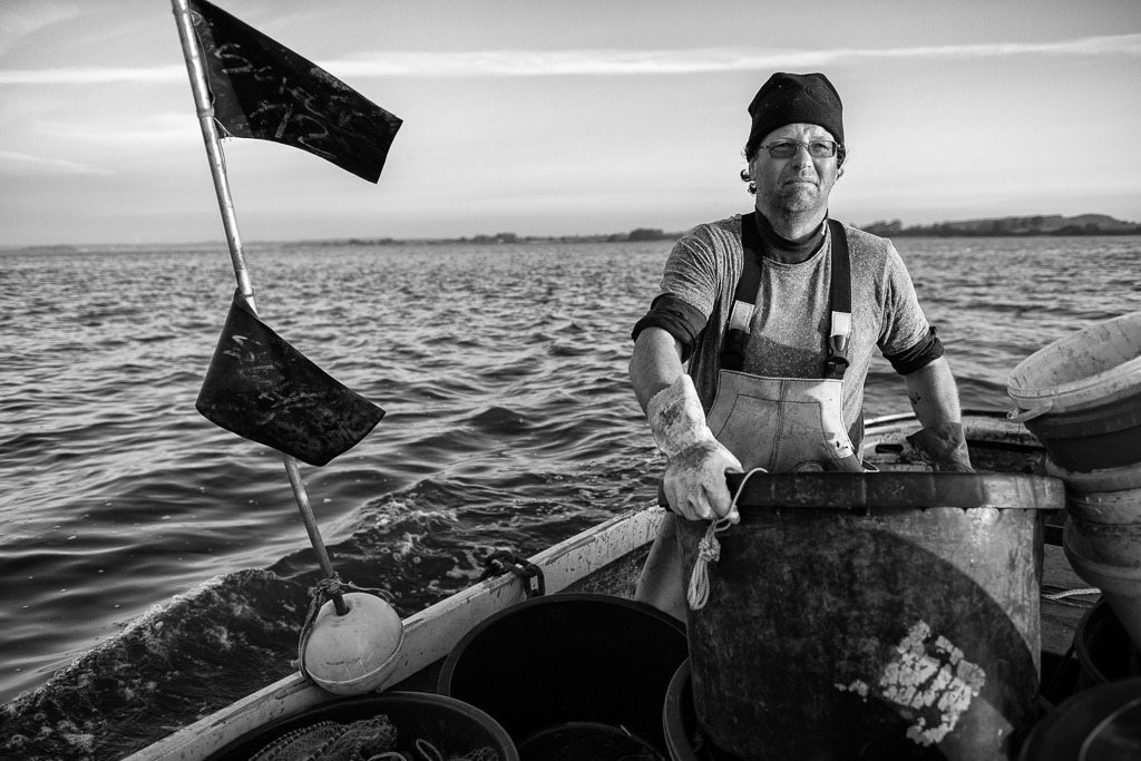 fischer-2019-089 | Matthias Nanz aus Schleswig ist einer der letzten Berufsfischer an der Schlei. Das Foto zeigt ihn auf seinem Boot frühmorgens Ende Mai beim Sortieren seiner Geräte auf der Fahrt zu den Fanggründen. - Realisiert mit Pictrs.com