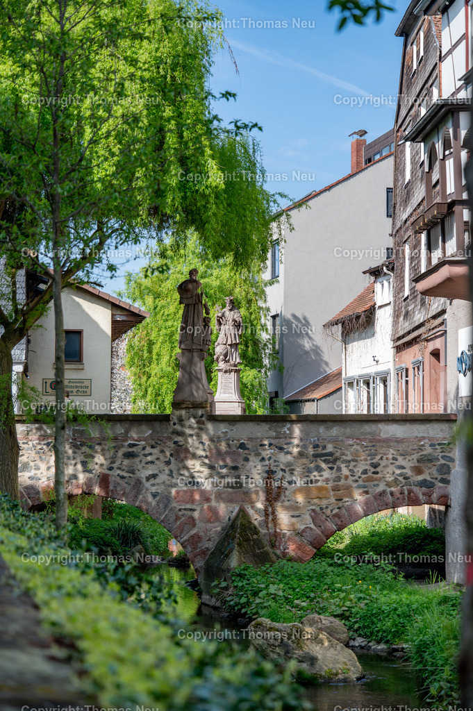 Mittelbruecke-Bensheim-Fotografie-Thomnas-Neu | bbe, Bensheim, Die unter Denkmalschutz stehende Mittelbrücke in Bensheim an der Bergstraße wurde 1732 über den Winkelbach errichtet. Die barocken Brückenheiligen prägen bis heute das Erscheinungsbild: Im Vordergrund ist der heilige Franz Xaver zu sehen, dem Betrachter den Rücken zugewandt, während auf der gegenüberliegenden Seite der heilige Johannes Nepomuk ivom frischen Grün dder Trauerweide  eingerahmt scheint.,Bild: THomas Neu