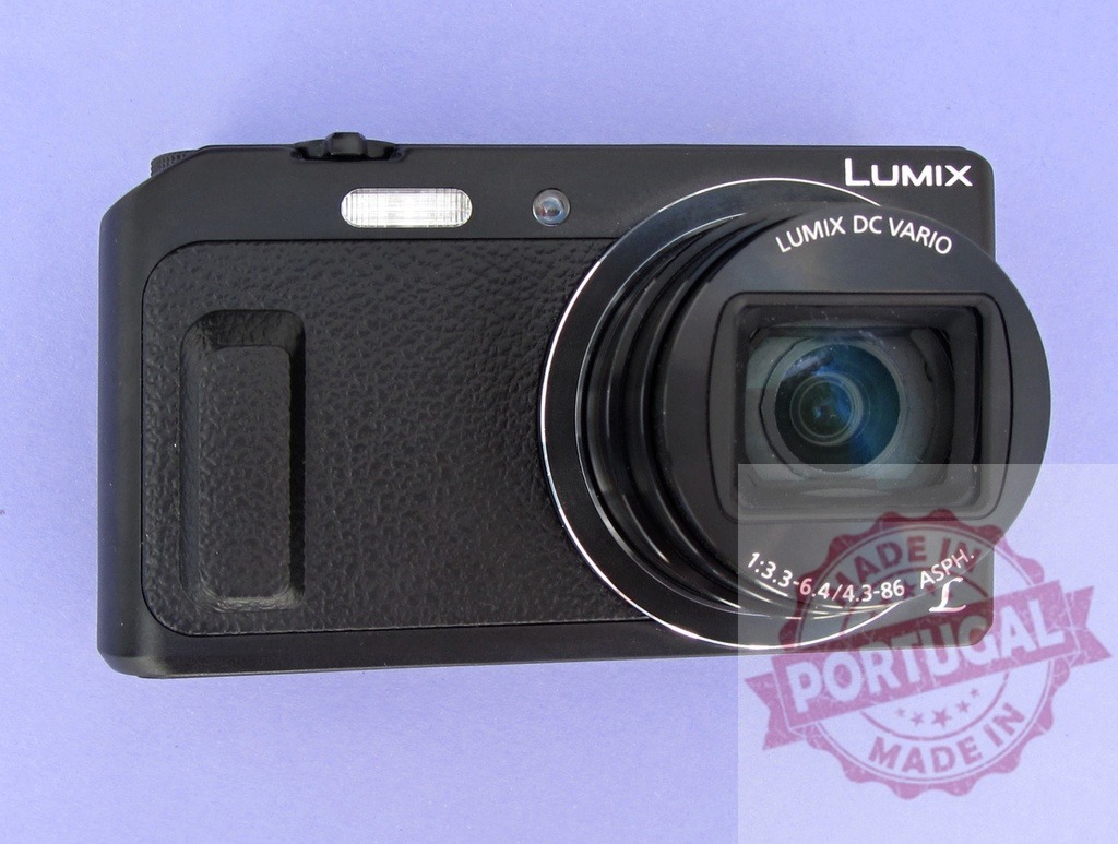 Panasonic Lumix digital compact camera on a plain background | Black Panasonic Lumix compact camera displaying its lens and built-in flash - Realized with Pictrs.com