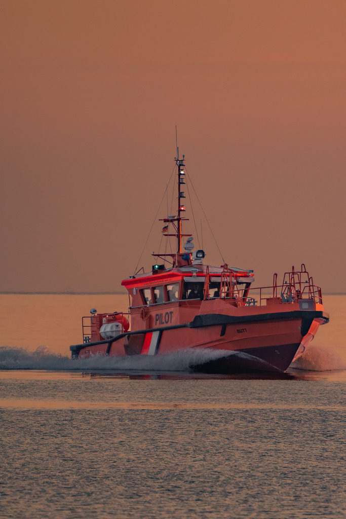 Seenotrettung vor der Küste von Warnemünde | Ein Seenotrettungskreuzer fährt im warmen Abendlicht über die Ostsee vor Warnemünde. Die kräftigen Farben des Schiffes heben sich deutlich von der ruhigen maritimen Stimmung ab. - Realisiert mit Pictrs.com