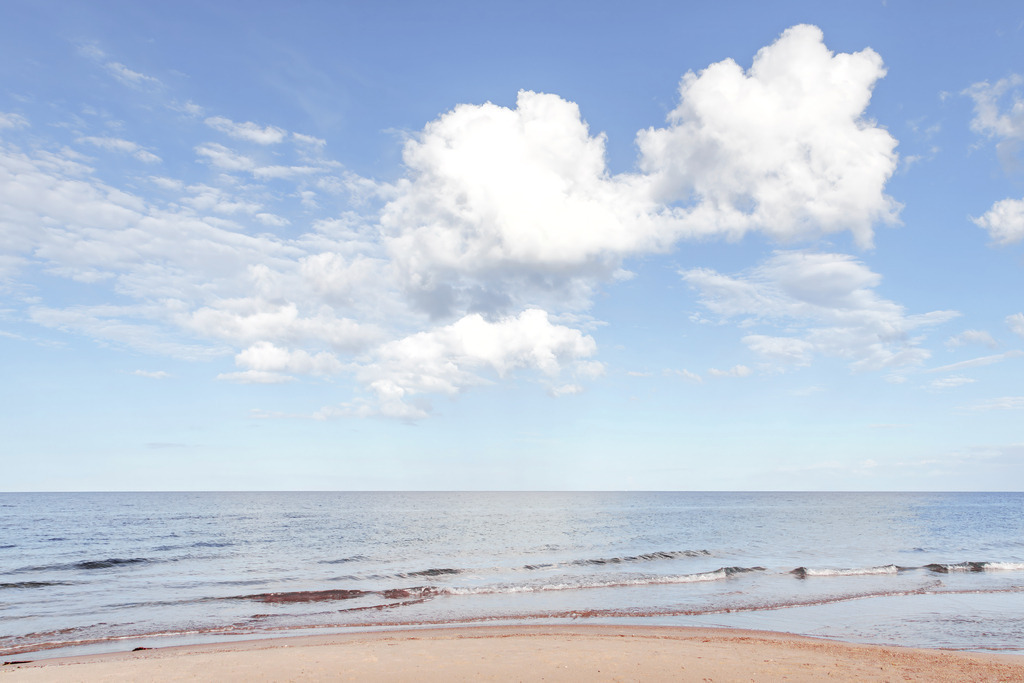 Sanfte Wolkenweite – Minimalistische Strandfotografie | Dieses Bild zeigt die See in ruhiger Klarheit: Eine feine Horizontlinie, sanfte Wellenstrukturen und helle, markante Wolkenformationen erzeugen eine stille, meditative Weite. Die reduzierte Bildsprache macht das Motiv zu einem harmonischen Beispiel minimalistischer Meeresfotografie – ideal als helles, exklusives maritimes Wandbild für die stilvolle Gestaltung moderner Interieurs.