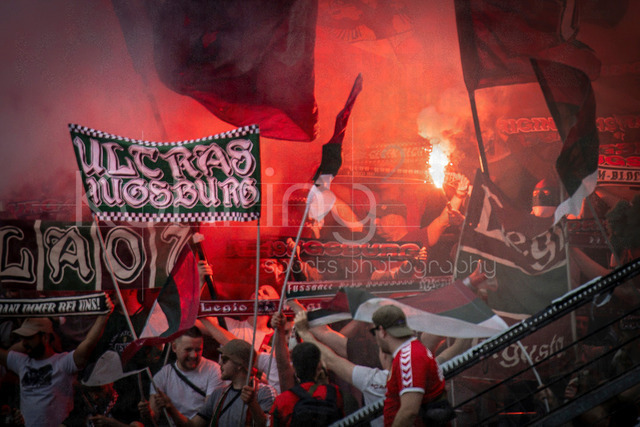 German Bundesliga, Bayer 04 Leverkusen vs. FC Augsburg, 18.04.2026 | LEVERKUSEN, GERMANY - APRIL 18, 2026 :  Augsburg Fans celebrating using pyrotechnics during the German Bundesliga match on gameday 30 between Bayer 04 Leverkusen vs. FC Augsburg at BayArena on April 18, 2026 in Leverkusen, Germany. DFL REGULATIONS PROHIBIT ANY USE OF PHOTOGRAPHS AS IMAGE SEQUENCES AND/OR QUASI-VIDEO.