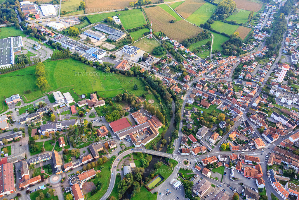 Aerial view: Course of the Moder and Les Ateliers du Sonnenhof Bischwiller (ESAT et EA) in Bischwiller in the state Bas-Rhin, France. – Photo: IMG_074306.jpg taken on 10/04/2014 by Werner Riehm/FLY-FOTO.com – Resolution of the original: 5472 x 3648 px – Les Ateliers du Sonnenhof