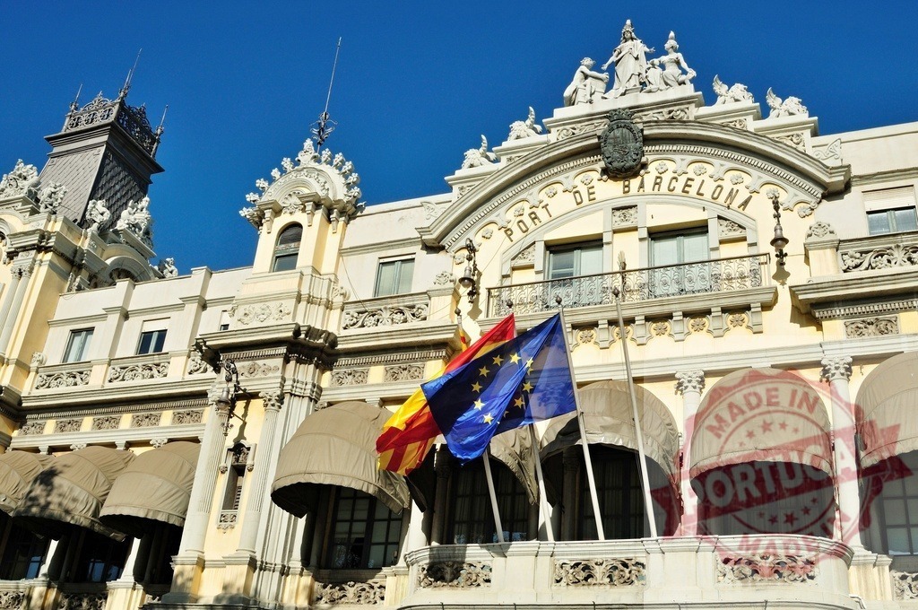 Port de Barcelona building displaying Catalonia and European Union flags. Spain - Barcelona | Ornate architecture of the Port Authority building under a clear blue sky - Realisiert mit Pictrs.com