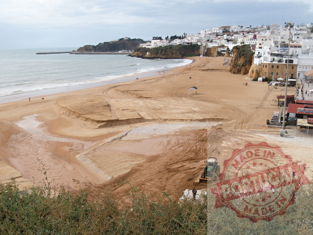 Bulldozer working on beach sand Albufeira Portugal | Albufeira Flood - discruction by weather problems Bulldozer working on beach sand below a coastal town and cliffs - Realisiert mit Pictrs.com
