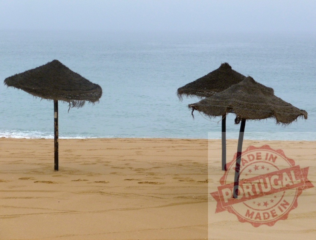 Straw umbrellas on quiet beach during off-season | Straw umbrellas standing on an empty beach with light waves under an overcast sky - Realisiert mit Pictrs.com
