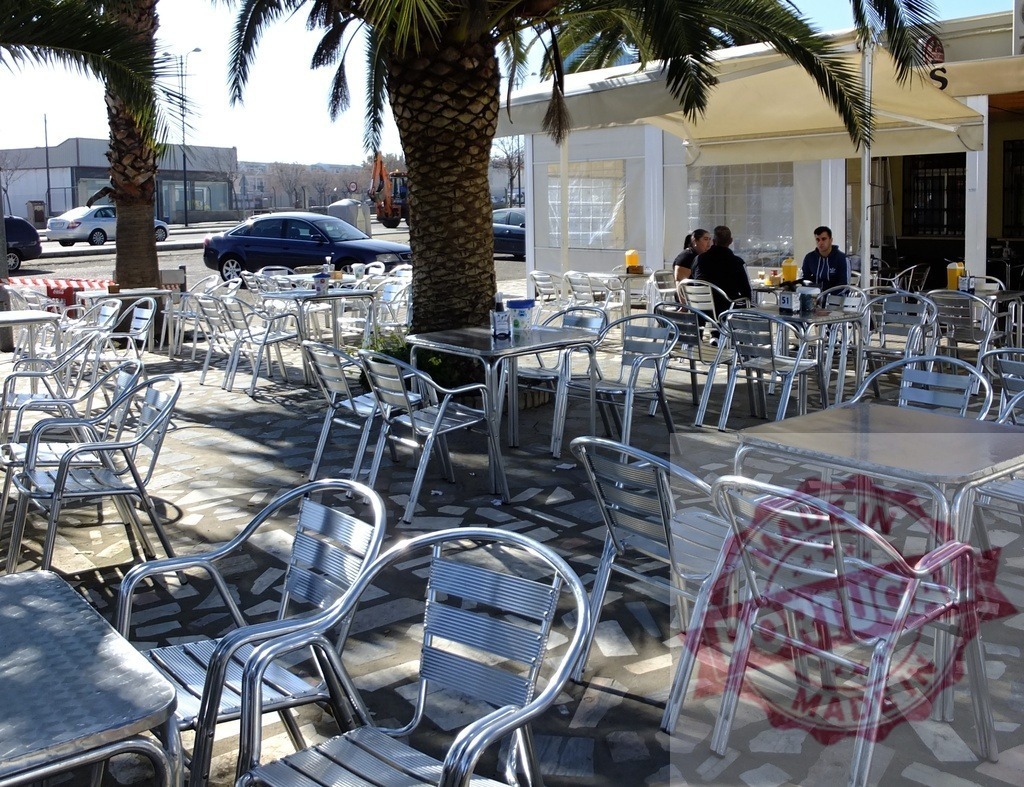 Outdoor cafe patio with empty tables and people | Palm trees shading an outdoor cafe patio with seating and people enjoying drinks - Realized with Pictrs.com