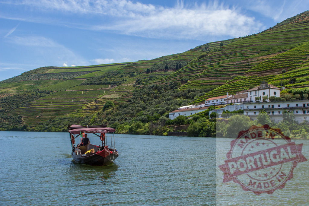 Rabelo boat navigating Douro River through terraced vineyards | Rabelo boat cruising Douro River in Portugal, passing terraced vineyards and a traditional winery on a sunny day - Realisiert mit Pictrs.com