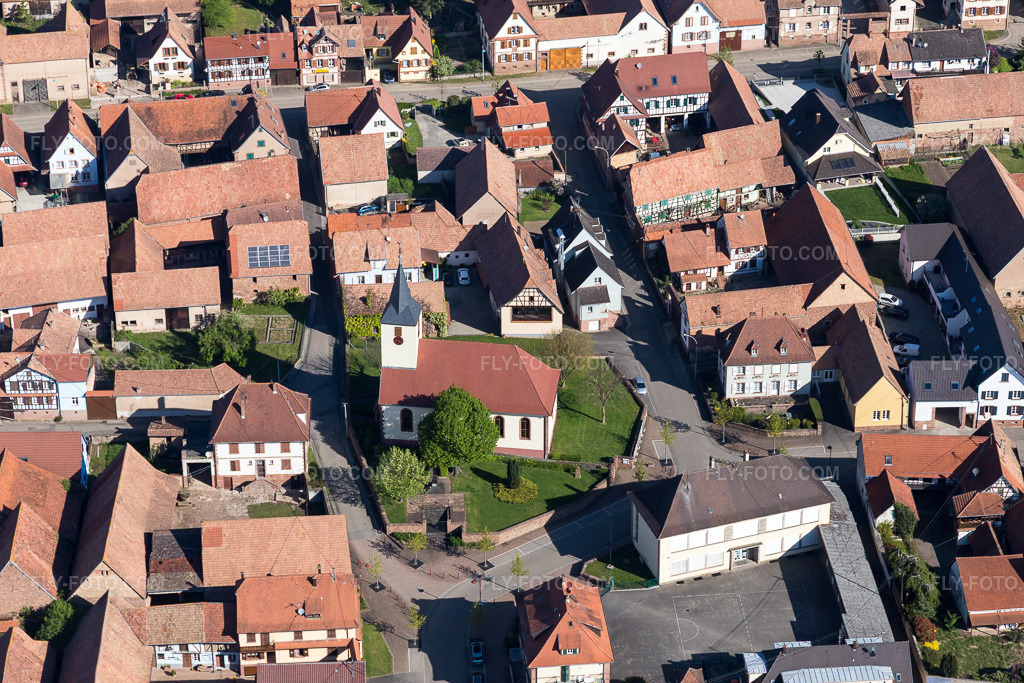 Aerial view: Church building in the village center in Uhrwiller in the state Bas-Rhin, France. – Photo: IMG_099450.jpg taken on 04/30/2017 by Werner Riehm/FLY-FOTO.com – Resolution of the original: 5472 x 3648 px