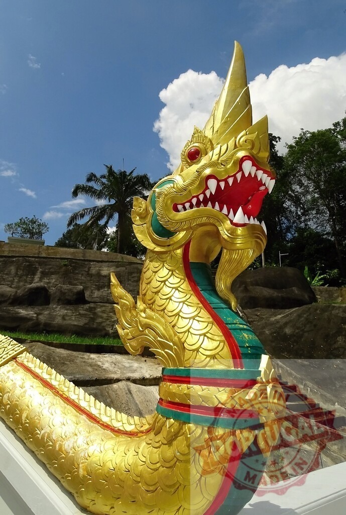 Golden naka statue decorating a temple in Thailand | Golden naka statue with red eyes and white fangs decorating a Thailand temple - Realized with Pictrs.com