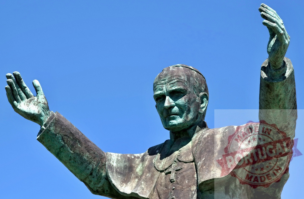 Pope John Paul II bronze statue blessing under blue sky | Pope John Paul II bronze statue stands with arms raised against a clear blue sky - Realisiert mit Pictrs.com