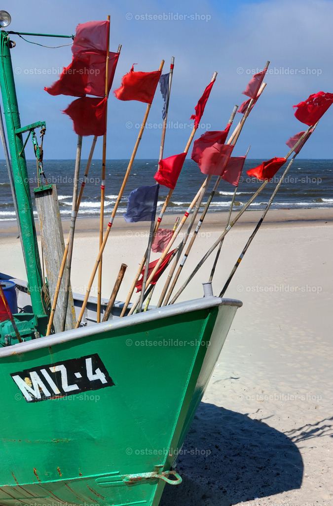 Netzbojen mit roten Fahnen an Bord eines Kutters  | Rote Bojenfahnen eines Fischkutters am Strand wehen im kräftigen Wind.