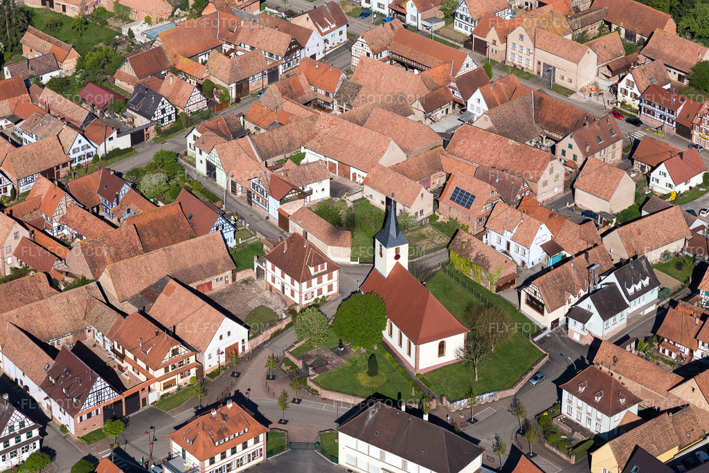 Aerial view: Church building in the village center in Uhrwiller in the state Bas-Rhin, France. – Photo: IMG_099445.jpg taken on 04/30/2017 by Werner Riehm/FLY-FOTO.com – Resolution of the original: 5472 x 3648 px
