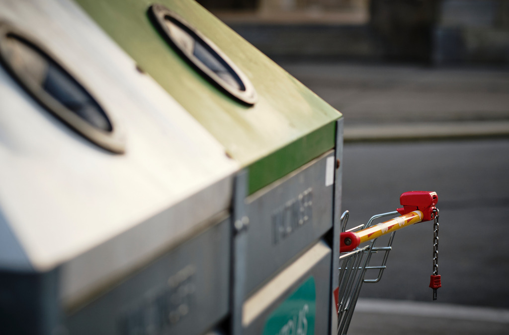 Müllplatz mit Glascontainer mit abgestelltem Einkaufswagen | Wien, Austria - December 10, 2019: Müllplatz mit Glascontainer mit abgestelltem Einkaufswagen. - Realisiert mit Pictrs.com