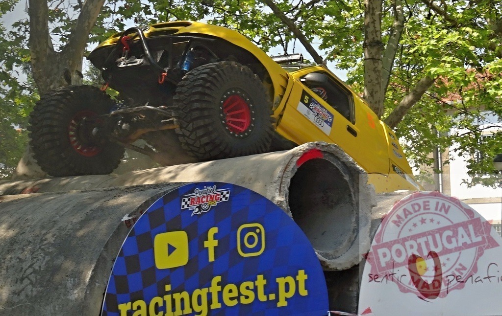 Yellow offroad vehicle climbing concrete pipes during racing festival | Powerful yellow offroad vehicle climbing concrete pipes during a racing festival - Realisiert mit Pictrs.com