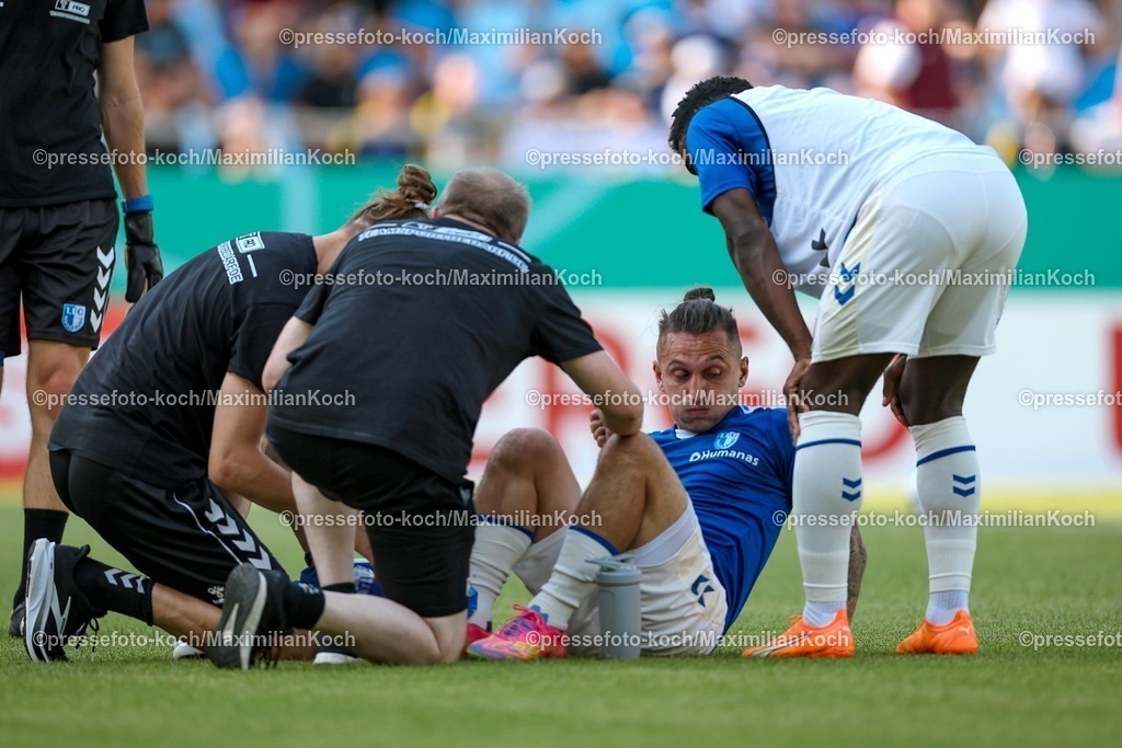 DFB15082501002 | 15.08.2025, Fußball, DFB-Pokal, 1. FC Saarbrücken - 1.FC Magdeburg, Ludwigsparkstadion, Saison 2025 2026: Baris Atik&nbsp;(1FC Magdeburg #23) liegt mit Schmerzen beim Aufwärmen auf dem Spielfeld und muss medizinisch versorgt werden  DFB regulations prohibit any use of photographs as image sequences and or quasi-video.