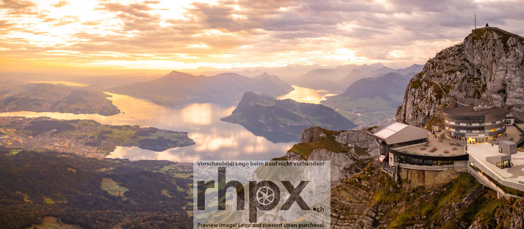 Morgenlicht am Pilatus Kulm | Gipfel. Weite. Morgenrot.Ein atemberaubendes Panorama vom Pilatus Kulm, während die erste Sonne den Vierwaldstättersee in flüssiges Gold taucht. Die markante Architektur auf dem Felsplateau steht in perfekter Harmonie zur unendlichen Tiefe der leuchtenden Alpenlandschaft.Wähle unter "Produktauswahl" dein Wunschformat: Vom klassischen Wandbild über Puzzle &amp; Tassen bis zum digitalen Download (z.B. als Handy-Hintergrund). - Realisiert mit Pictrs.com